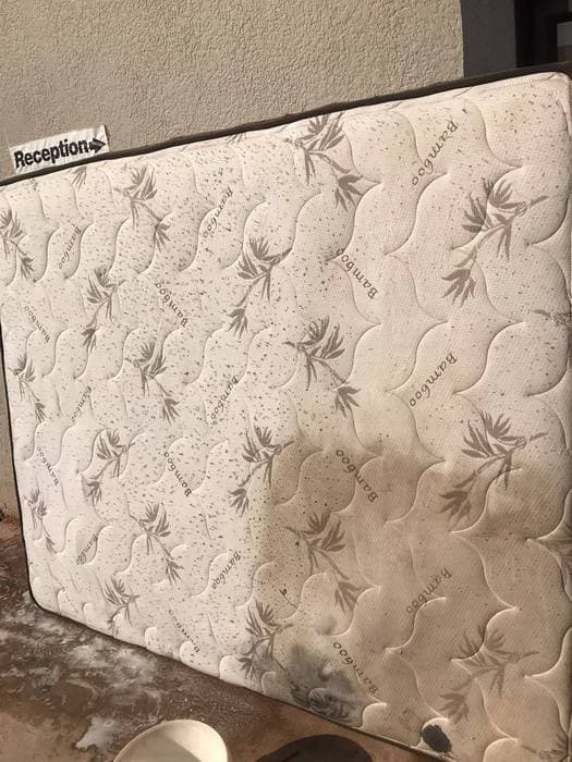 A mattress split down the middle, one half still stained and one half cleaned bright white.