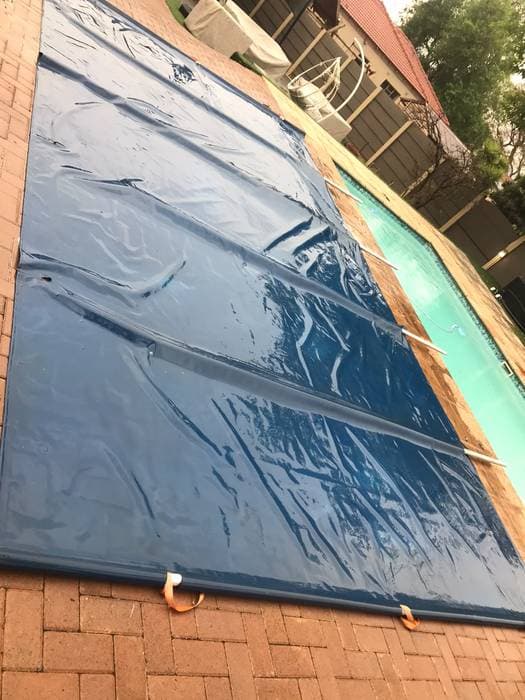 A large pool cover, cleaned and laid out beside the pool.
